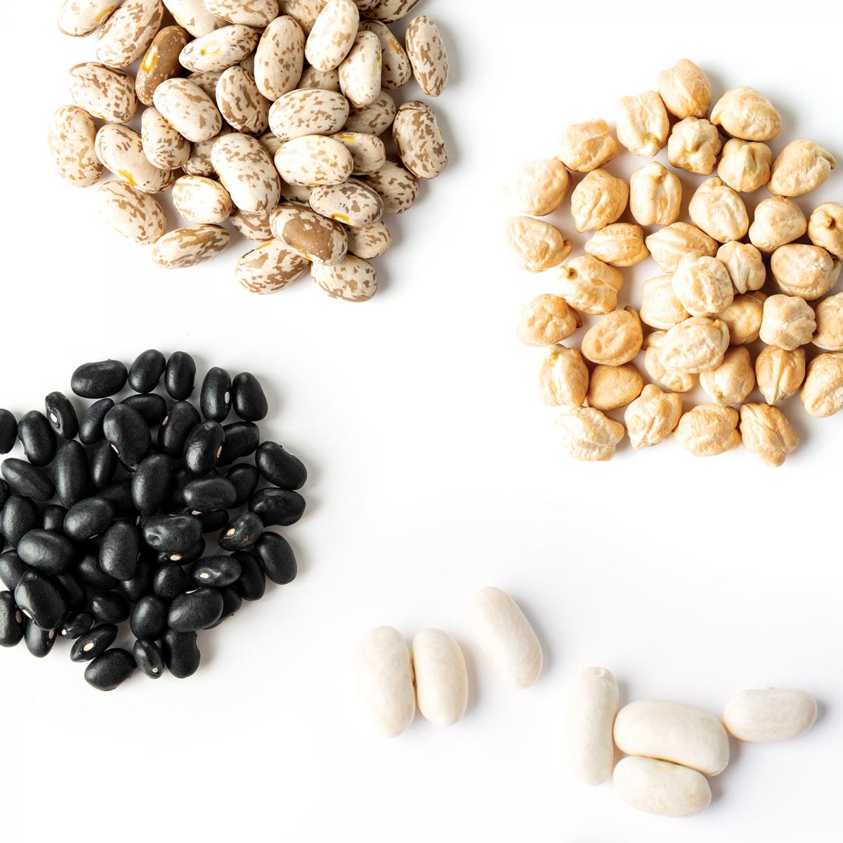 Four small piles of different kinds of dried beans