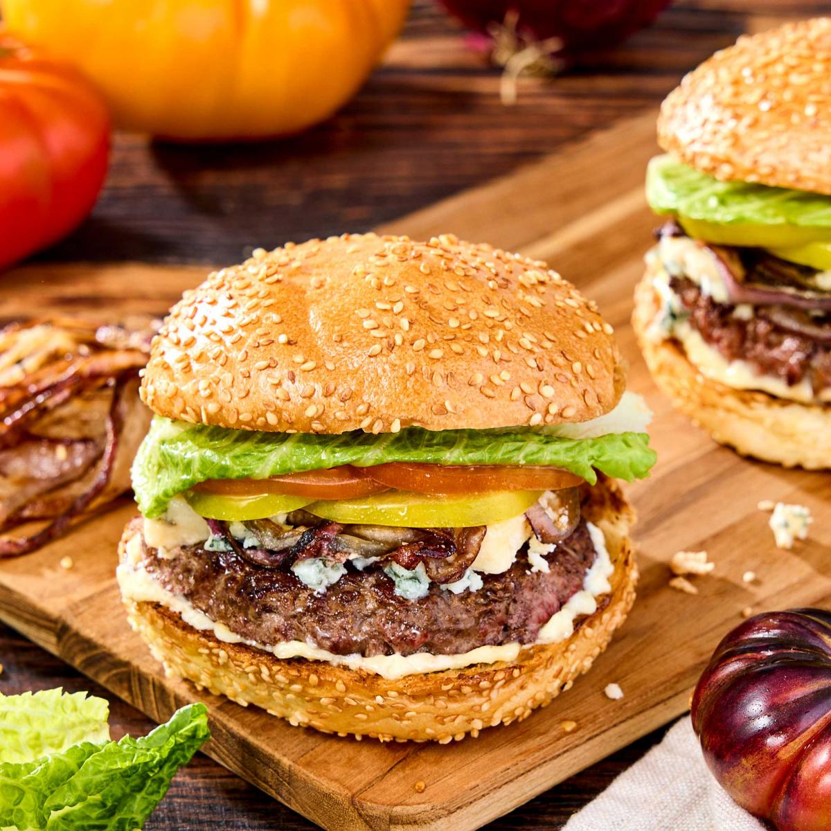 Grilled hamburger with blue cheese wedges, heirlooms tomatoes, romaine lettuce and bakery sesame seed kaiser rolls
