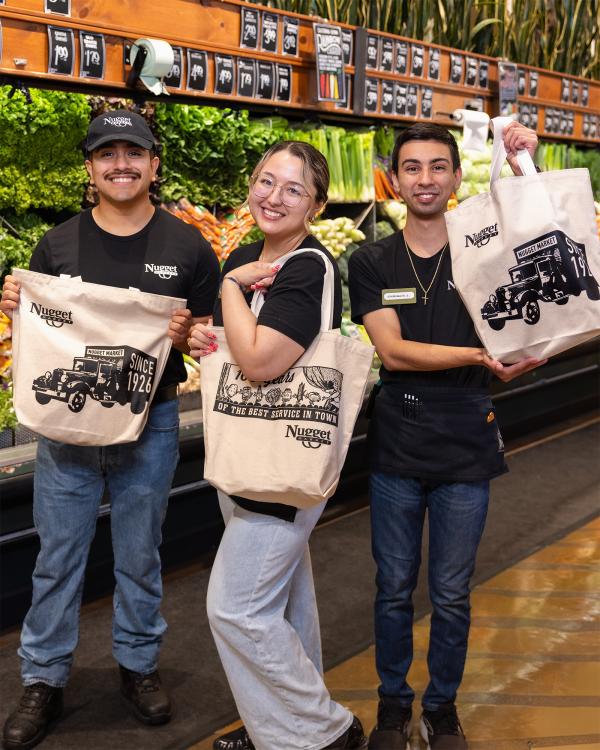 Three Nugget Market associates holding our reusable canvas bags