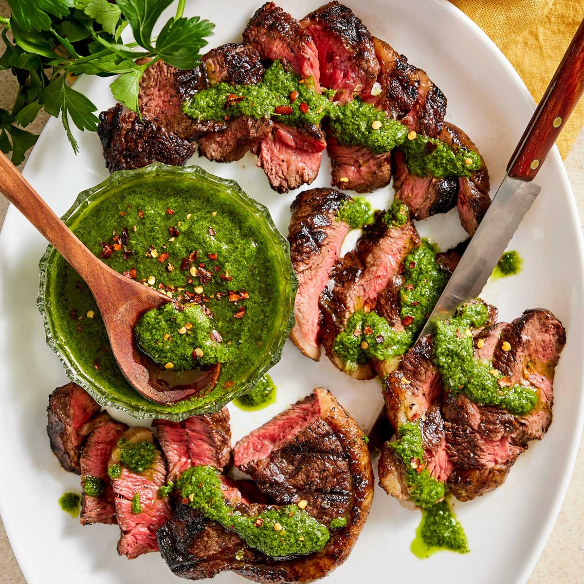 Chimichurri Dressing in small bowl drizzled alongside picanha rump roast steak slices