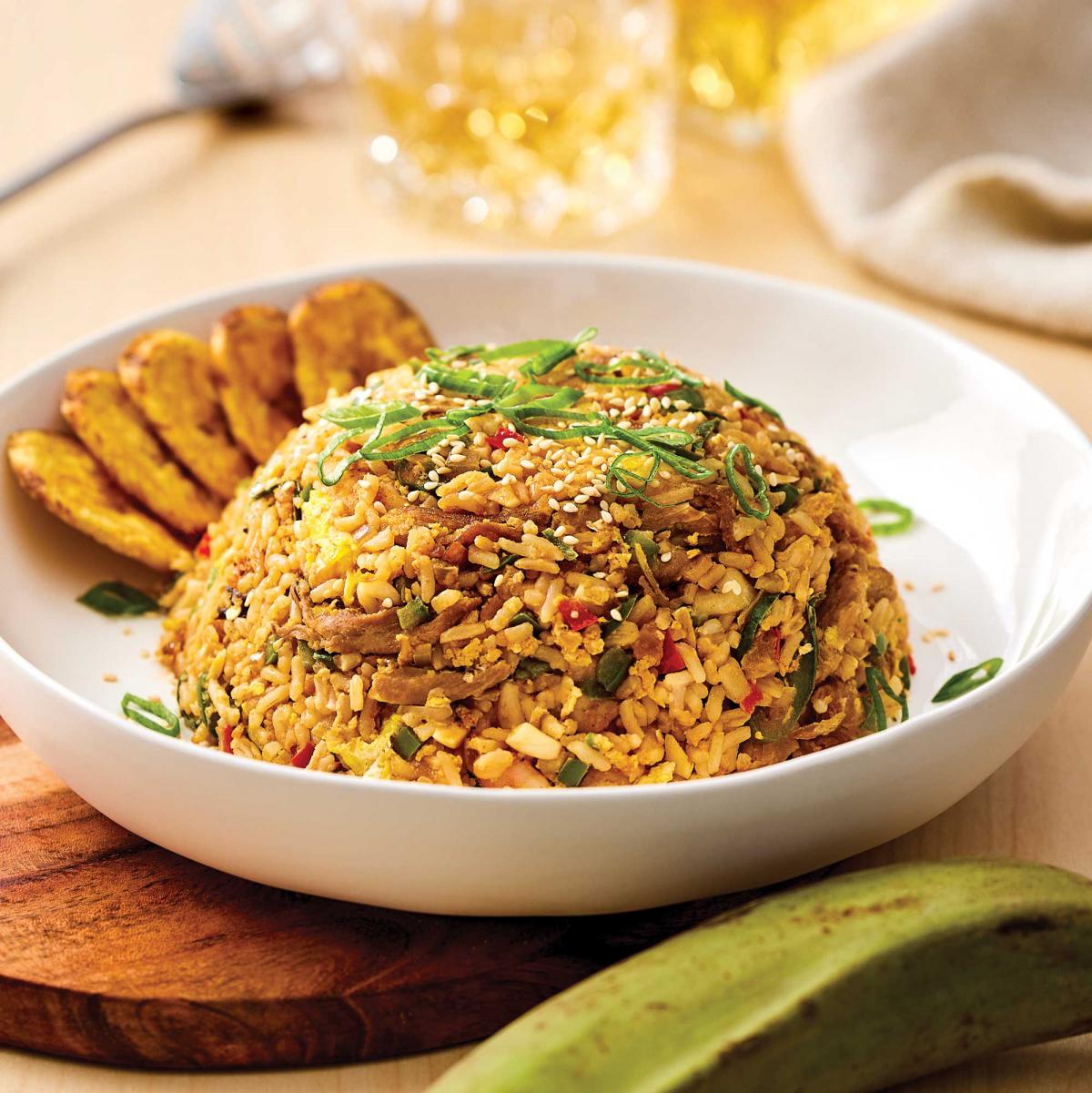 Cuban Fried Rice with fried Plantains slices in a bowl with some tquila in the backgorund