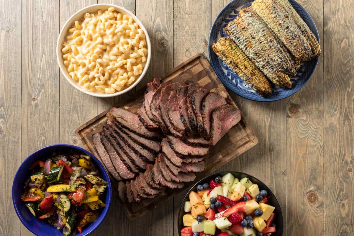 Top down view of tri-tip, corn on the cob and sides