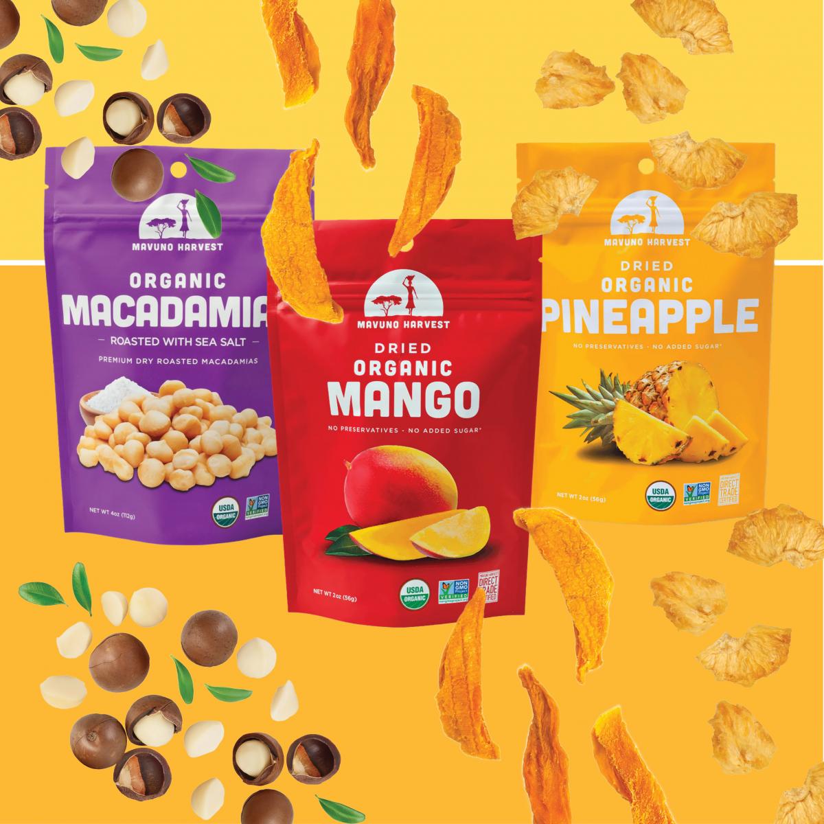 Three bags of Mavuno Harvest dried fruit and nuts with macadamia nuts, dried mango, and dried pineapple around them