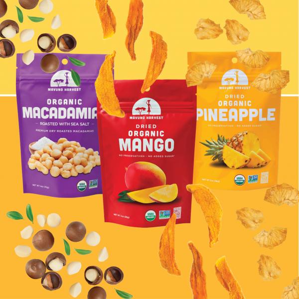 Three bags of Mavuno Harvest dried fruit and nuts with macadamia nuts, dried mango, and dried pineapple around them