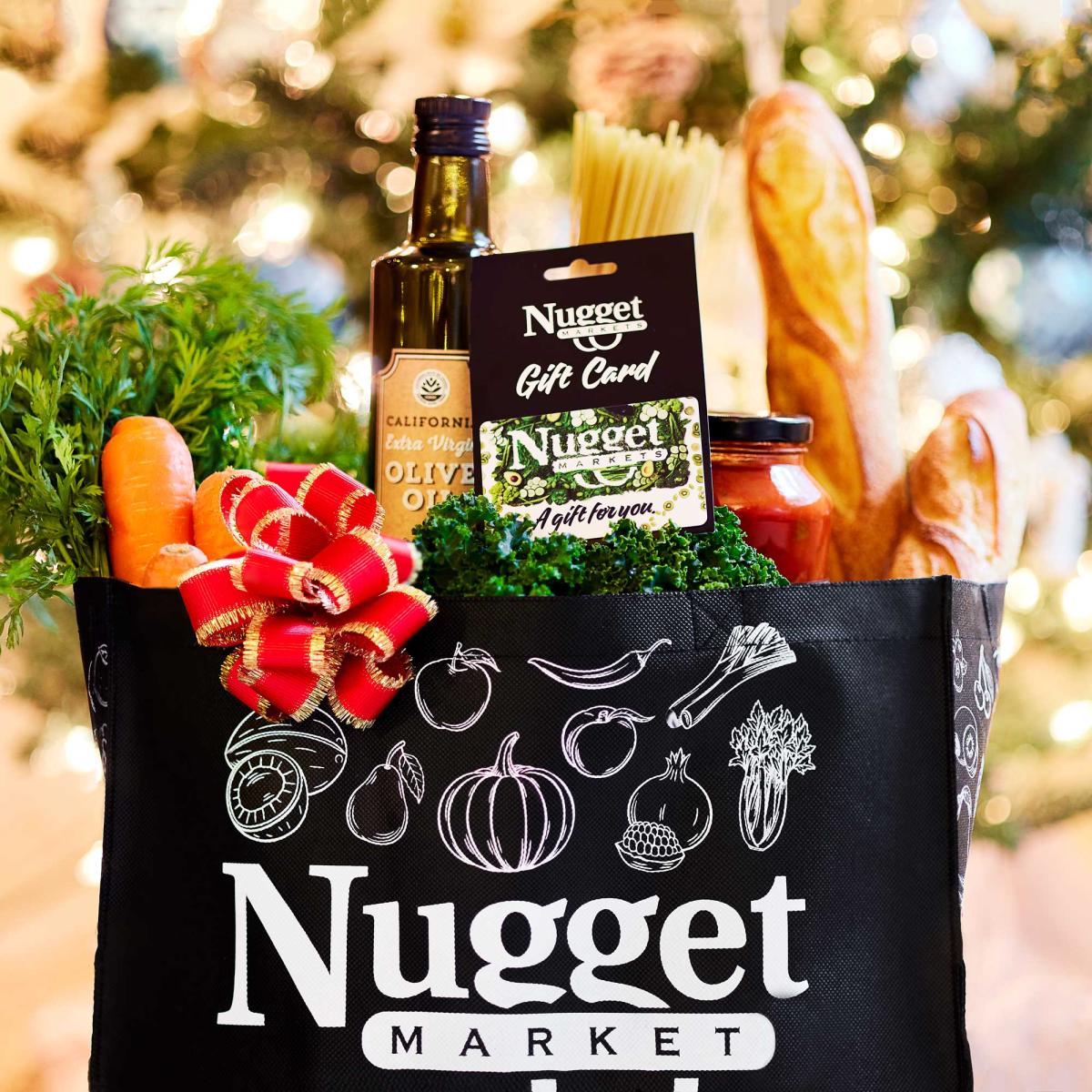 Reusable Nugget Tote Bag with groceries inside and a gift card in front of a Christmas tree