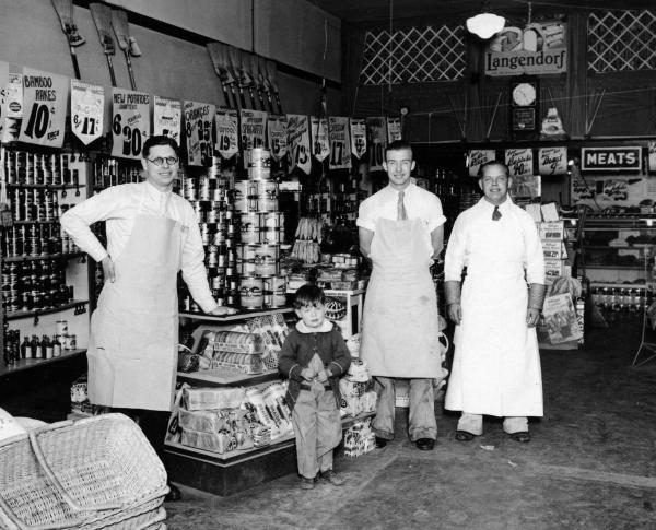 Black and white photo of three men and a boy standing inside the old Nugget Market grocery store