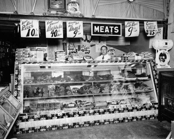 Vintage black and white photo of Nugget Market meat counter with associate behind it