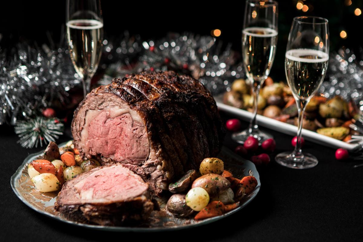 standing rib roast with glasses of sparkling wine and Christmas decorations