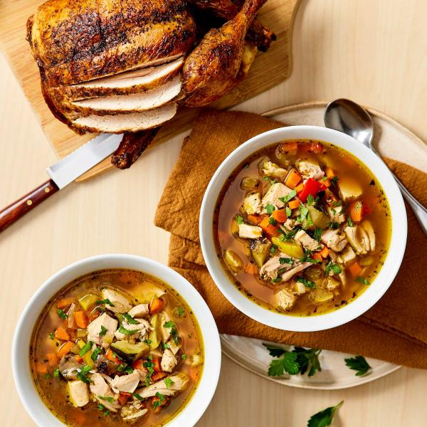 Rotisserie Chicken Soup in two bowls with a sliced chicken to the side