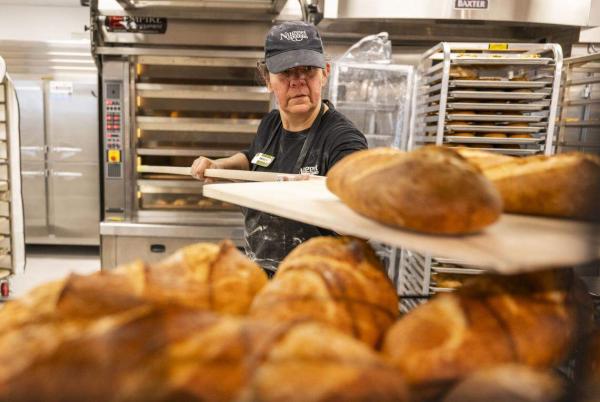 Baker Vanessa moves fresh bread loaves from the oven at Nugget Market's newest store in Rocklin