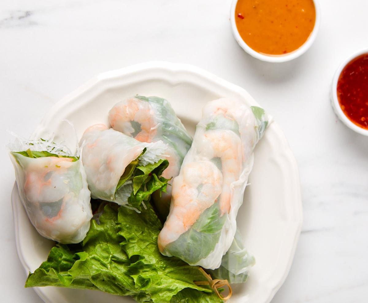 shrimp spring rolls on a plate with dips on the side