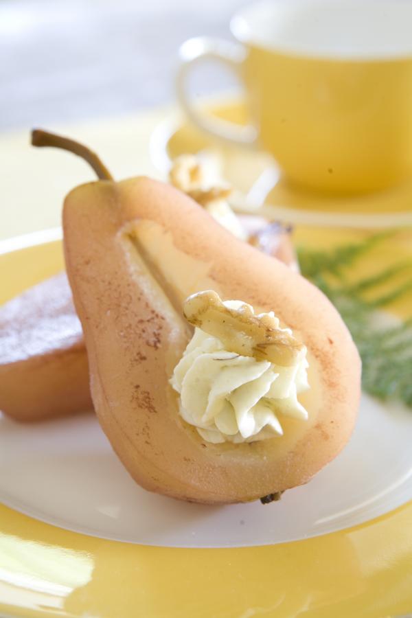 port-poached pear half stuffed with blue cheese on a plate with a yellow teacup in the background