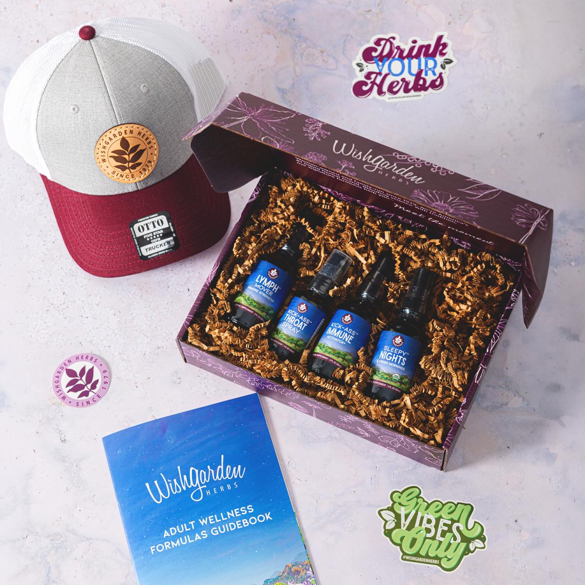 Box of four Wishgarden Herbs bottles next to branded brochure, stickers, and a hat